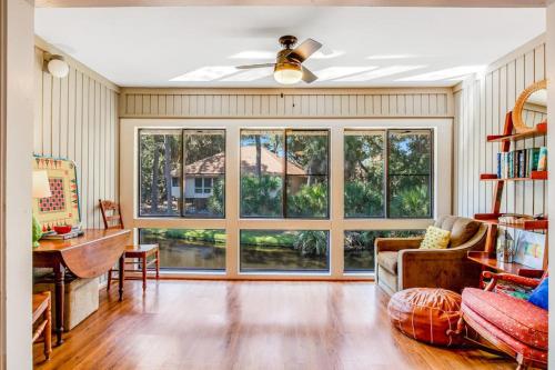 a living room with a ceiling fan and large windows at The Pirate Den in Edisto Beach
