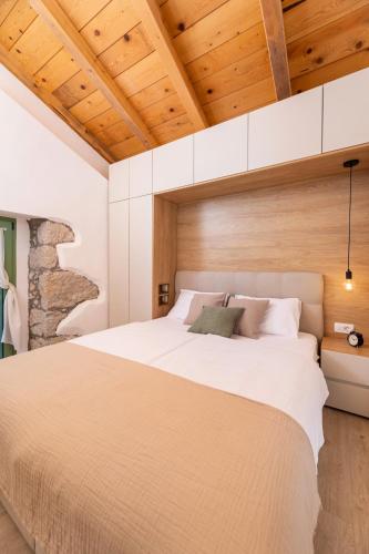 a bedroom with a large white bed with wooden ceilings at Hidden House Porta in Krk