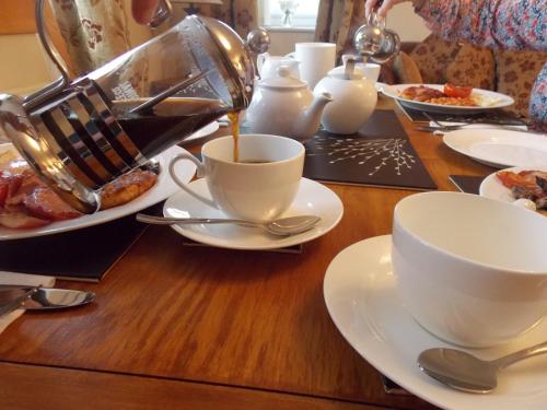 a table with cups of coffee and plates of food at Craig Eithin B & B in Holyhead