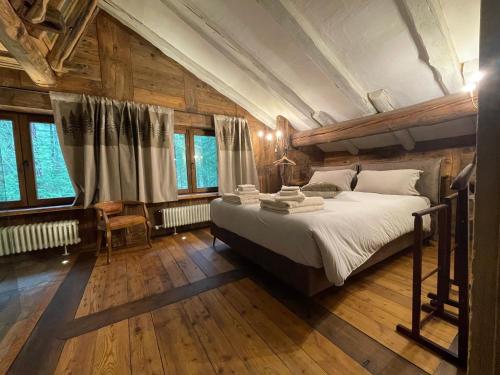 a bedroom with a large bed with wooden floors and windows at Rêve sur le lac in Rhêmes-Notre-Dame