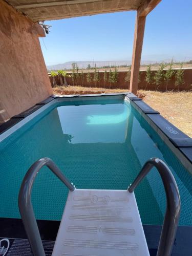 a swimming pool with a chair in the water at AISHAMA Healing House in Aït Ourir