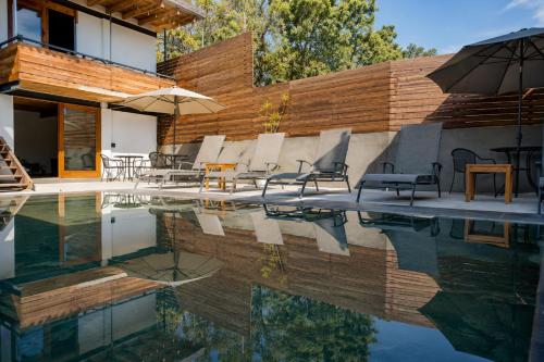 a pool with chairs and an umbrella next to a building at Villa Maria Hotel in Valle de Bravo