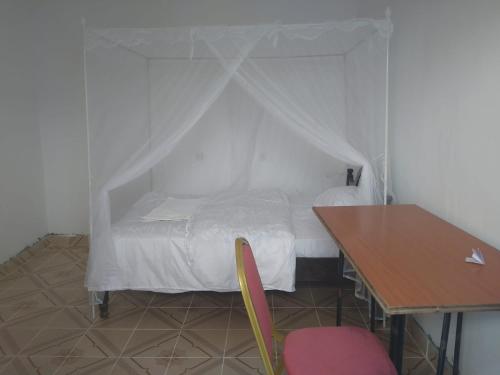 a bedroom with a bed with a desk and a table at The HIVE in Kitui