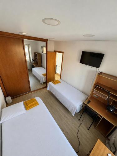 a hotel room with two beds and a television at Casa cidade e piscina in Coimbra