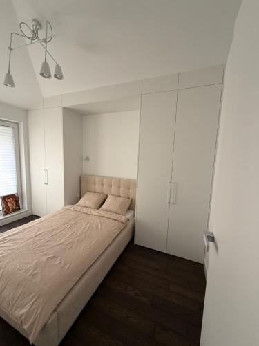 a bedroom with a large bed and white cabinets at Apartament Brzeg in Augustów