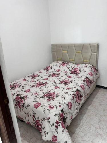 a bed with a floral comforter in a bedroom at Meknès,hameriya in Meknès