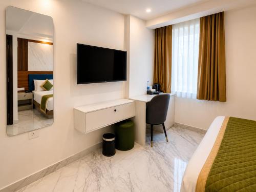 a hotel room with a bed and a desk with a television at Sabu's Grand Royale - Thampanoor in Trivandrum