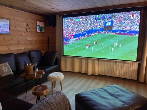 a living room with a large screen tv with a soccer game at Catered chalet ideal location centre of Alpe d'Huez - 4 en-suite bedrooms - sauna - private home cinema - 10 people in L'Alpe-d'Huez