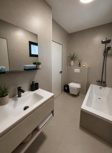 a bathroom with a sink and a tub and a toilet at סוויטות אקווה איירפורט בוטיק & גרדן - By SEAELO in Eilat
