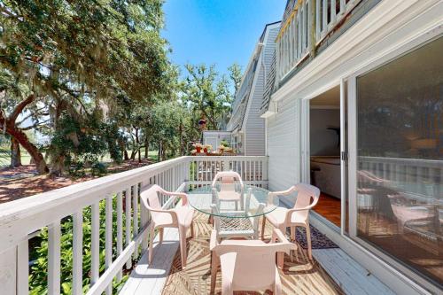 a patio with a glass table and chairs on a balcony at Driftwood Villa - 262 in Edisto Beach