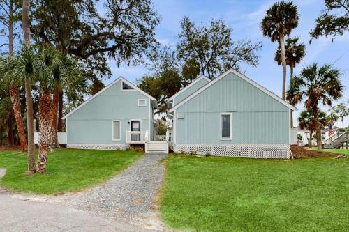 a white house with palm trees in a yard at Sea La Vie in Edisto Island