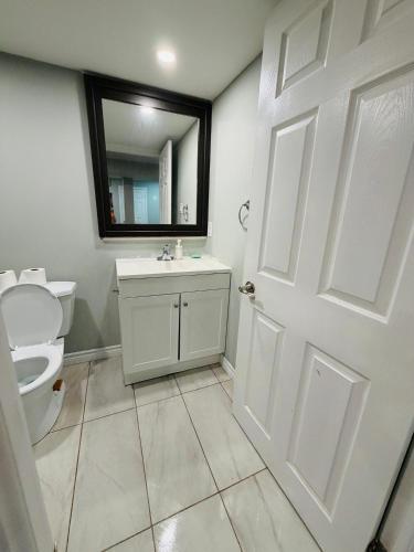 ein Badezimmer mit Toilette, Waschbecken und Spiegel in der Unterkunft Niagara Falls 2 Bedrooms 1 and half washroom Luxury Basement Apartment in Thorold