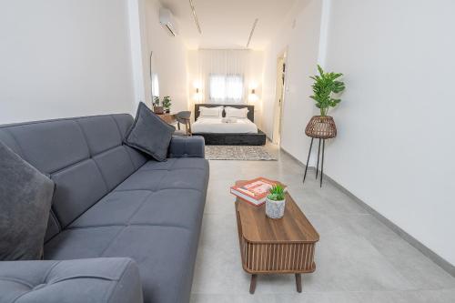 a living room with a blue couch and a table at פלואלס - וילת יוקרה עם 4 חדרי שינה ובריכה מחוממת וגקוזי in Shahar