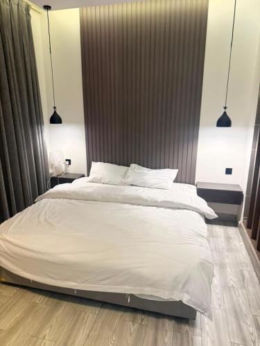 a large white bed in a bedroom with two lamps at شاليهات سمو بارك in Taif