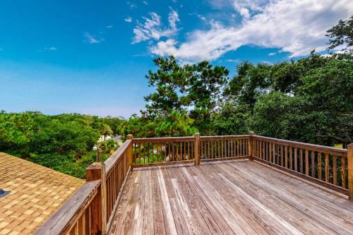 a large wooden deck with trees in the background at Slow Drift in Edisto Beach