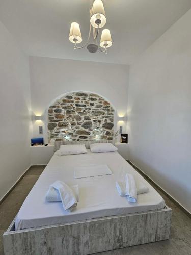 a bedroom with a large bed with a stone wall at Aspalathos I & ΙΙ in Kamárion