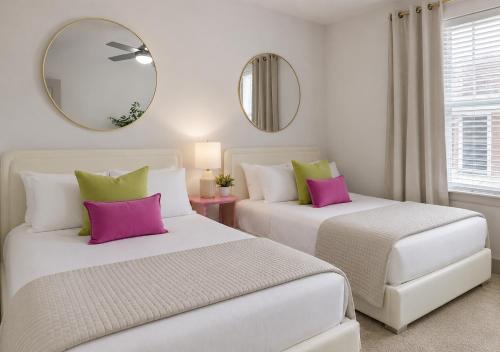 two beds with pink and green pillows in a room at Walk to Toyota Stadium in Frisco