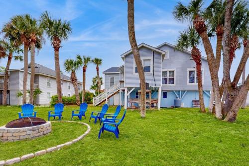 a group of blue chairs in a yard with palm trees at Myra's Cottage in Edisto Beach