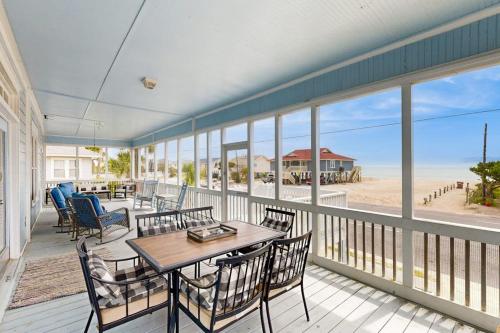 a porch with tables and chairs and a view of the beach at Myra's Cottage in Edisto Beach