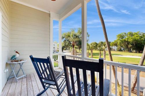 a porch with two chairs and a table and palm trees at King Cotton Villa 17 in Edisto Beach