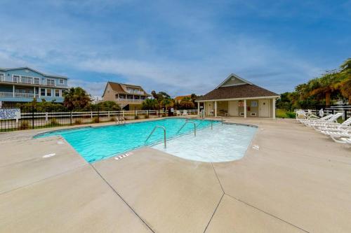 a swimming pool with white chairs and a house at The Retreat 7A in Edisto Beach