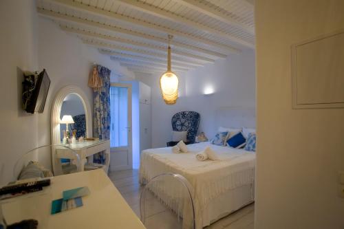 a white bedroom with a bed and a table at Fino Amore Private Jacuzzi Suite in Mykonos Town in Mikonos