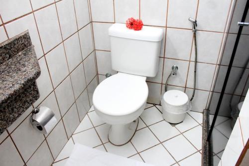 a bathroom with a toilet with a red flower on it at Coroa Bella Praia Hotel in Coroa Vermelha