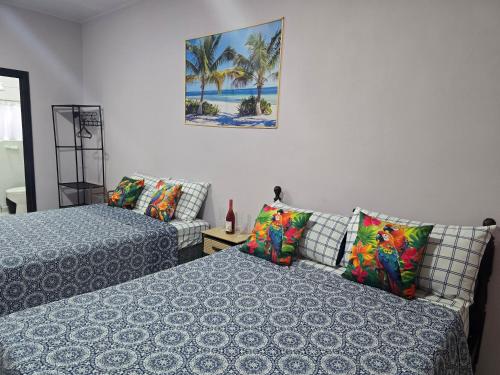 a bedroom with two beds and a painting on the wall at Apartamentos Torres Manuel Antonio in Manuel Antonio