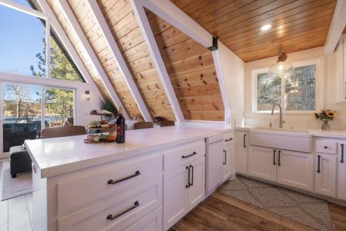 a kitchen with white cabinets and a wooden ceiling at Cove Lakeside Jacuzzi, Central AC, Stunning View in Big Bear Lake