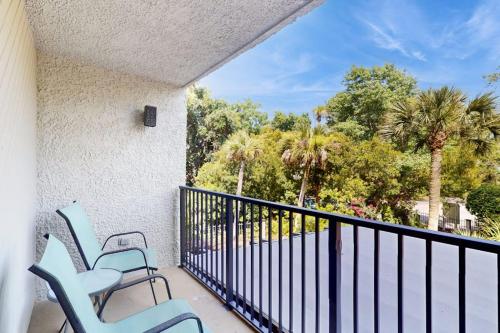 a balcony with two blue chairs and trees at Xanadu D8 in Hilton Head Island