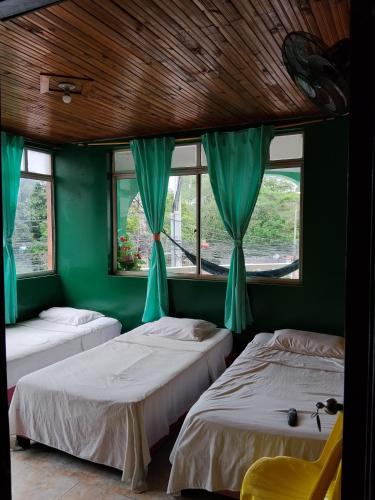 two beds in a room with green walls and windows at Hospedaje Mundial in Villeta