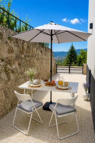 a white table with two chairs and an umbrella at Casa da Covilhã - Pedra e Lã in Covilhã