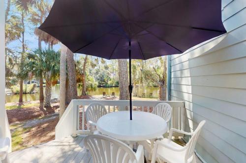 a table and chairs on a porch with an umbrella at Egrets Pointe 491 in Edisto Beach