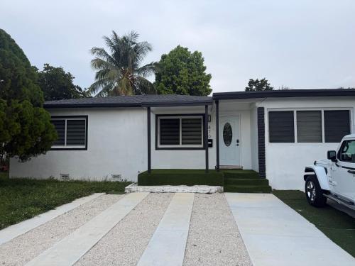 a white house with a car parked in front of it at Casa relax in North Miami Beach