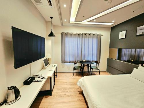 a hotel room with a bed and a desk with a television at If Business Hotel in Changwon