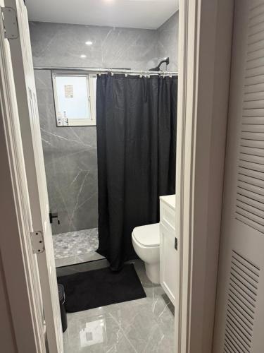 a bathroom with a black shower curtain and a toilet at Casa paz in North Miami Beach