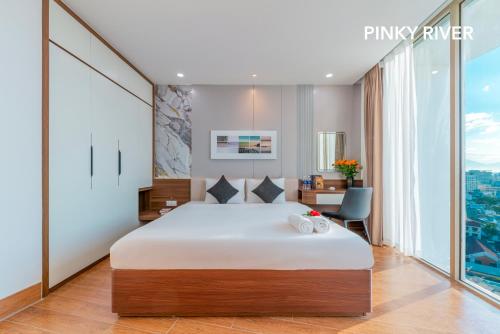 a bedroom with a large bed and a desk at PinkyRiver in Danang