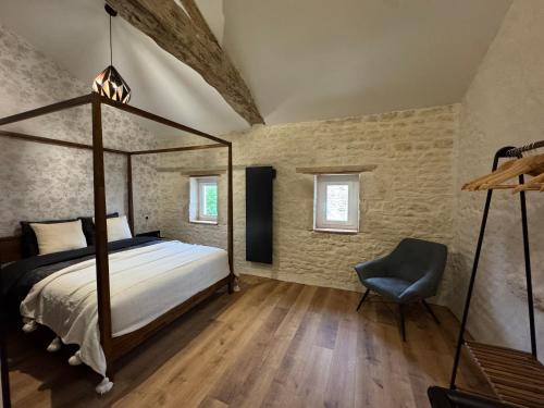 a bedroom with a bed and a chair at Les nids de la chevêche in Saint-Pierre-de-Juillers