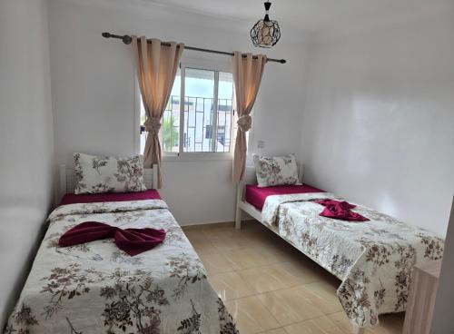 a bedroom with two beds and a window at Oualidia résidence Ben zeroual in Oualidia