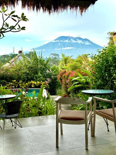 a patio with tables and chairs and a view of a mountain at Amrita Villa Sidemen in Sidemen