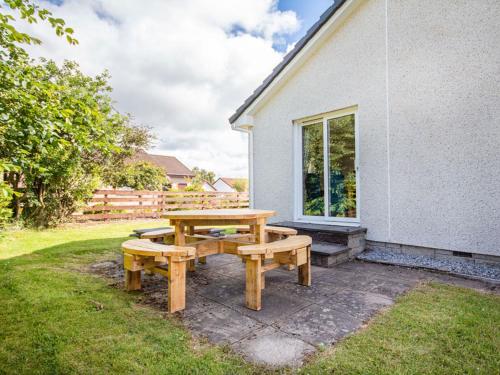 a picnic table and bench outside of a house at Caledon in Aviemore