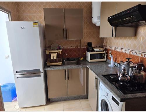 a kitchen with a white refrigerator and a stove at Oualidia résidence Ben zeroual in Oualidia