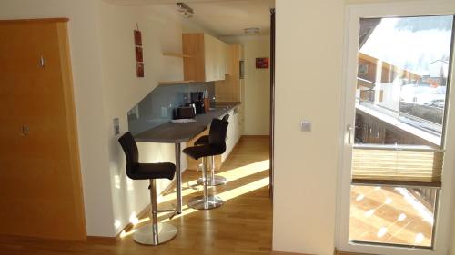 a kitchen with two bar stools and a counter at Appartements Gassner in Bruck an der Großglocknerstraße