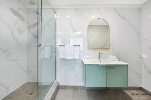 a bathroom with a shower and a sink and a mirror at Mid City Motel Warrnambool in Warrnambool