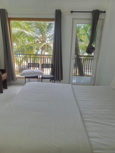 a bedroom with a large white bed and two chairs at La Paraso Agatti in Agatti