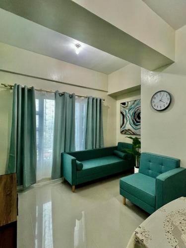 a living room with a green couch and a clock at ONE PAVILLION PLACE in Cebu City