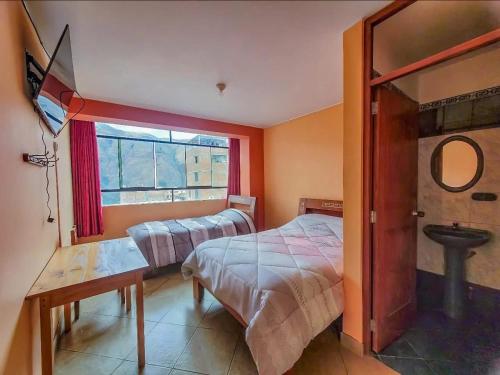 a bedroom with two beds and a window at Hostal Huagancu in Huari