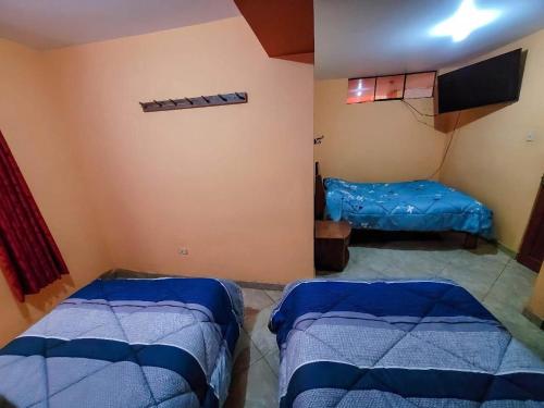 a room with two beds and a tv in it at Hostal Huagancu in Huari