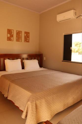 a bedroom with a large bed with a window at Pousada Recanto dos Buritis in Manhã