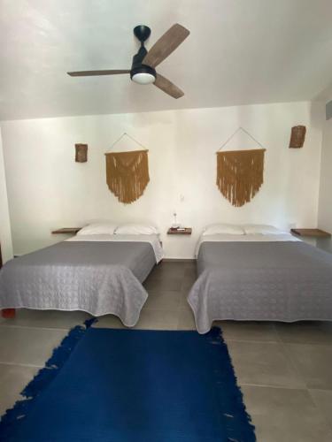 two beds in a room with a ceiling fan at Casa Baloo in El Cuyo